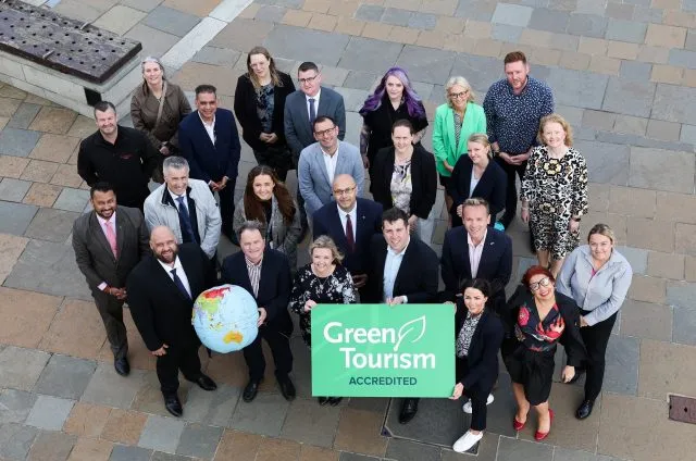 Visit Belfast Green Partners standing in a group outside holding a Green Tourism Sign and A Globe Image